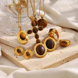 Conjunto de joyas ojo de tigre con colgantes dorados y pendientes en bandeja de seda