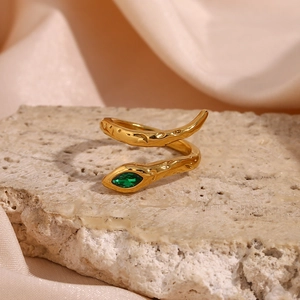 Macro detail of gold-plated snake ring with green zircon eye and hammered texture