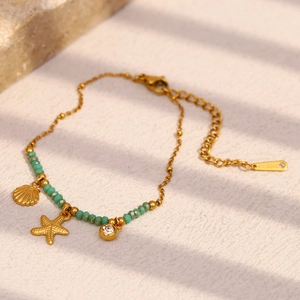 Detail of 18K gold-plated starfish and shell charms with turquoise beads on jewelry
