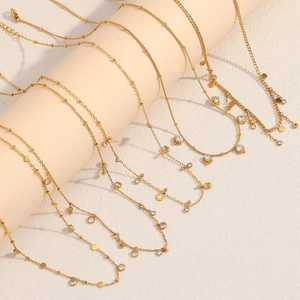 Detail of 18K gold plated necklaces featuring crystal charms and sunburst pendants