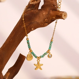 Detail of 18K gold starfish and shell charms with green beads on a branch