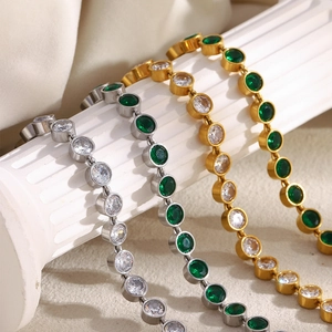 Detail of four tennis bracelets in gold and silver finish with emerald and white stones