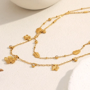 Macro shot of 18K gold plated necklace with delicate floral and leaf charms detailing