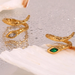 Detailed macro view of gold plated snake rings with hammered texture and green gemstones