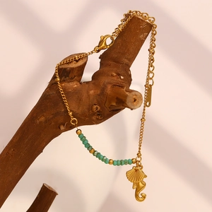 Gros plan du bracelet hippocampe en or 18 carats avec perles turquoises sur bois