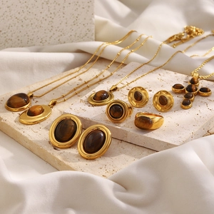 Detalle de set de joyas vintage chapado en oro 18K con piedra ojo de tigre y cruz fina