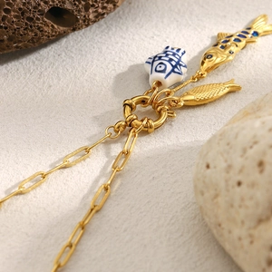 Λεπτομέρεια από χρυσά μενταγιόν ψάρια 18K με αλυσίδα συνδετήρα και κούμπωμα ελατηρίου