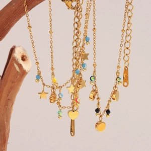 Detail of 18K gold-plated stainless steel bracelets with stars and heart charms on wood