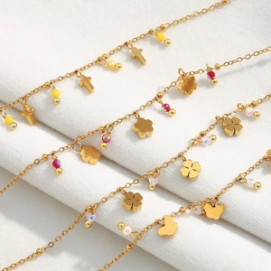 Detailed close-up of 18K gold-plated bracelets with cross, clover, and butterfly charms