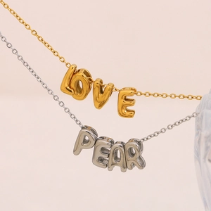 Vue macro des pendentifs lettres en or et argent sur des chaînes en acier inoxydable