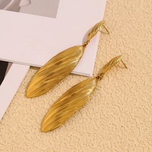 Close-up of gold-plated leaf earrings featuring detailed vertical texture on metal