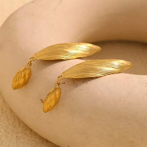 Macro detail of golden vintage leaf earrings showing textured stripes and metallic finish