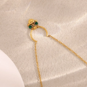 Detail eines 18K vergoldeten Herzanhängers mit grünen Perlen und feiner Metallkette