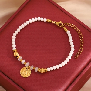 Détail du bracelet en perles avec breloque pièce dorée et pierres blanches taillées