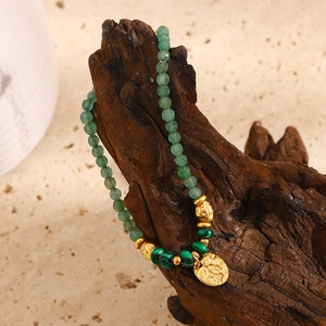Détail macro du pendentif pièce plaqué or 18K et perles de malachite sur le bracelet