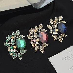 Vintage olive leaf brooches with emerald, ruby, and sapphire stones on a black sweater