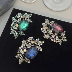 Vintage olive leaf brooches with emerald, ruby, and sapphire gemstones on black velvet