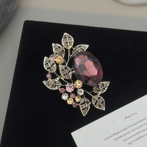 Detail of vintage olive leaf brooch with purple gemstone and multicolored rhinestones