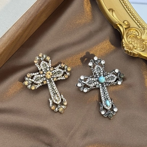 Gros plan de broches croix vintage en strass avec sculpture évidée sur de la soie brune