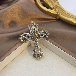 Détail de la broche croix baroque vintage avec cristaux ambrés et relief en métal doré