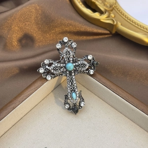 Détail macro de la broche croix vintage avec pierres bleu d'eau et strass brillants
