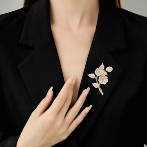 Elegante spilla a rosa dorata con cristalli scintillanti su un blazer nero da donna