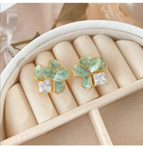 Detailaufnahme der Blumenohrringe mit grüner Emaille und quadratischem Zirkon in Geschenkbox