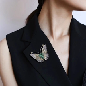 Détail d'une broche papillon avec pierres vertes sur le revers d'un costume noir