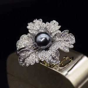 Broche fleur de rose scintillante avec perle noire et diamants pavés sur fond noir profond