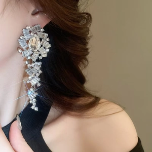 Détail de boucles d'oreilles fleur en cristal argenté avec longs glands sur le mannequin
