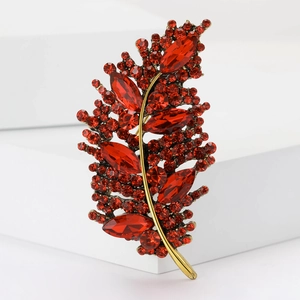 Macro shot of red marquise-cut crystal leaf brooch with elegant gold plating details