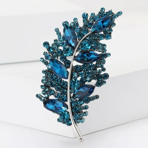 Macro shot of silver leaf brooch with deep blue rhinestones and elegant curved crystals