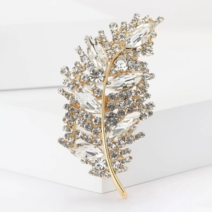 Close-up of golden leaf brooch with sparkling pavé rhinestones and crystal details