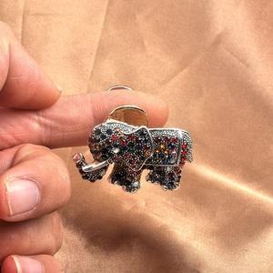 Colorful elephant brooch with vibrant rhinestones shown for scale against silk