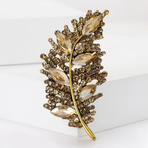 Macro shot of gold leaf brooch with champagne diamonds and amber crystals on white stand