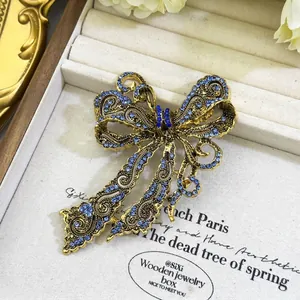 Vintage gold bowtie brooch with light blue crystals and elegant floral filigree details