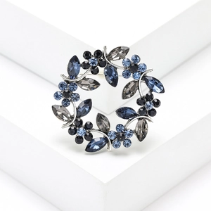 Broche couronne rameau d'olivier argentée avec cristaux bleu foncé et gris sur socles blancs