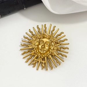 Detail of vintage gold sun goddess brooch with intricate matte finish relief work