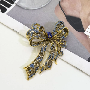 Detail of vintage hollow bow brooch with blue rhinestones and gold alloy finish