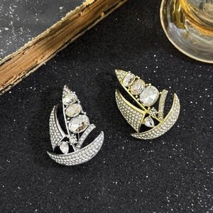 Sparkling sailboat brooches in gold and silver with rhinestones on a black background