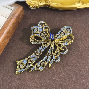 Vintage gold bowknot brooch with blue rhinestones displayed on a velvet background