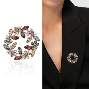 Élégante broche couronne en cristal avec strass multicolores sur mannequin et fond blanc