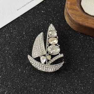 Macro detail of silver sailboat brooch with pave-set rhinestones and oval crystals