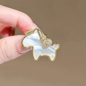 Macro detail of horse brooch with mother-of-pearl inlay and sparkling gold pendant