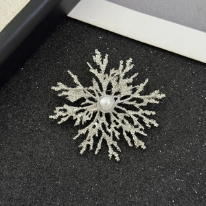 Detailed close-up of silver snowflake brooch with elegant pearl on black textured background