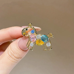 Detail of a horse brooch with multi-colored zircons and a polished golden metal finish