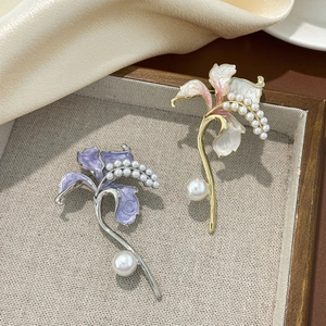 Squisite spille a forma di giglio con petali smaltati e perle su vassoio in legno testurizzato