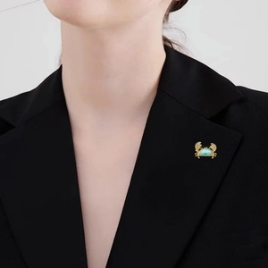 Broche crabe exquise avec pierre bleue et cristaux blancs sur le revers d'une veste
