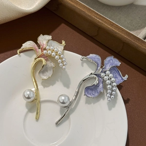 Dettaglio di spille floreali in smalto con perle eleganti e petali su piatto di ceramica