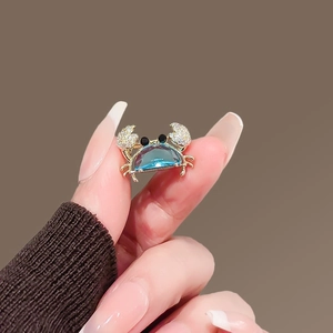 Gros plan d'une mini broche crabe avec gemme bleue et pattes serties de cristaux